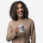Elbows Up In Canada Canadian Flag white ceramic 15oz mug held by male model showing 'Elbows Up In Canada' circle design.