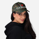 Front of I Love Canada green camo classic dad hat on female model showing words 'I Love Canada' embroidered white with red heart for the word 'love'.