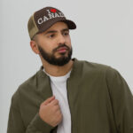 Words 'I Love Canada' embroidered white with a red heart for the word 'love' on front of a brown and khaki retro trucker hat on a male.