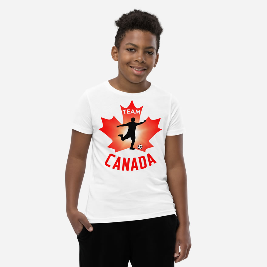 Front of Boy's Soccer white youth staple t-shirt on boy. Player kicking ball silhouette on red maple leaf. Says Team Canada.