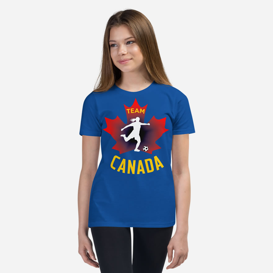 Front of Girl's Soccer true royal youth staple t-shirt on girl. Player kicking ball silhouette on red maple leaf. Says Team Canada.