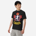 Front of Men's Soccer black heavyweight tee on man. Player kicking ball silhouette on red maple leaf. Says Team Canada.