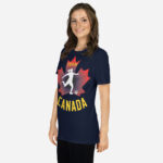 Front of Women's Soccer navy unisex t-shirt on woman. Player kicking ball silhouette on maple leaf. Says Team Canada.