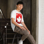 Front of Canada Red & White Maple Leaf t-shirt white softstyle tee on model. Word Canada on top with red bars & white maple leaf.