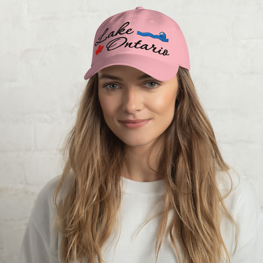Front of Lake Ontario pink classic dad hat on model showing 'Lake Ontario' embroidered black along with red maple leaf & blue wave.