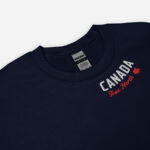 Close up of navy Canada True North sweatshirt with words Canada in white, True North red and a red maple leaf curved along neckline.