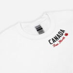 Close up of white Canada True North sweatshirt with words Canada in white, True North red and a red maple leaf curved along neckline.
