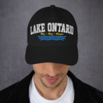 Front of Lake Ontario Canada black dad hat on model showing 'Lake Ontario' atop wavy lines embroidered white with red maple leaves.