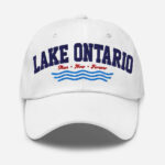 Front of Lake Ontario Canada white dad hat showing words 'Lake Ontario' atop wavy lines embroidered navy above red maple leaves.