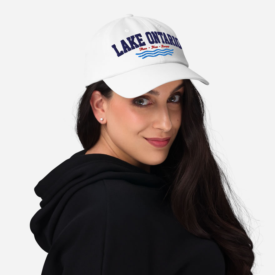Front of Lake Ontario Canada white dad hat on model showing 'Lake Ontario' atop wavy lines embroidered navy with red maple leaves.