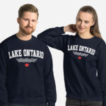 Front of Lake Ontario navy unisex crew neck sweatshirt on models with words Lake Ontario atop wavy lines (in white) above a red maple leaf.