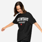 Front of Lake Ontario black heavyweight t-shirt on model with words Lake Ontario atop wavy lines (in white) above a red maple leaf.
