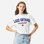 Front of Lake Ontario white heavyweight t-shirt on model with words Lake Ontario atop wavy lines (in navy) above a red maple leaf.
