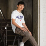 Front of Lake Ontario white t-shirt on model with words Lake Ontario atop wavy lines (in navy) above a red maple leaf.